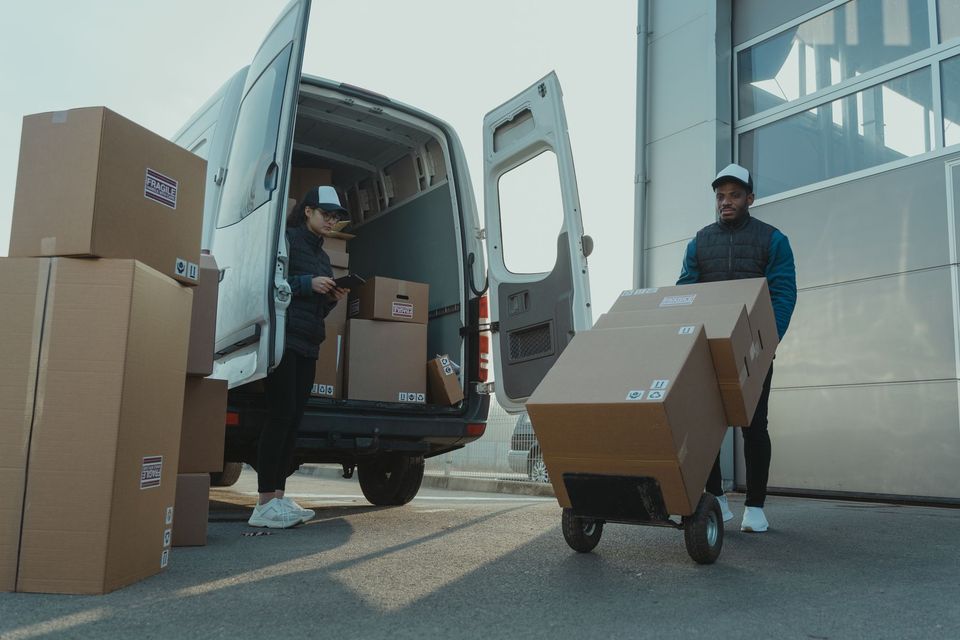 A mover loading stacked packing boxes into the back of a moving van